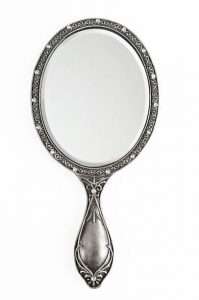 A silver handheld mirror, a tool that comes in handy when sugaring at home for hair removal.