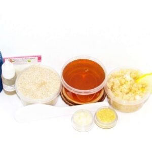 The home sugaring hair removal starter kit comes with a 2 oz tub of soft sugaring wax, a tub of Coconut Lemon Sugar Body Scrub, and a tub of Colloidal Oatmeal Brown Sugar Dry Body Scrub, a small bottle of pure aloe vera, a pouch of cornstarch, an applicator, denim strips, and the pristine white surface is garnished with coconut shavings, lemon zest and slices.