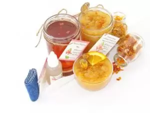 A collection of skincare products including an 8 oz mason jar of sugaring wax and Orange Calendula Herbal Sugar Scrub, the included applicator, bottle of pure aloe vera, denims strips and accompanied by smaller jars of calendula petals and dried orange zest on a white background.