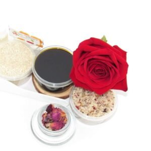 The home sugaring hair removal starter kit comes with a 2 oz tub of firm sugaring paste, a tub of Red Rose Petal Sugar Body Scrub, and a tub of Colloidal Oatmeal Brown Sugar Dry Body Scrub, a small bottle of pure aloe vera, a pouch of cornstarch, an applicator, and a glass bowl garnished with a red rose bloom.