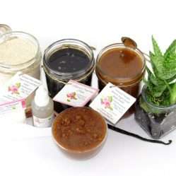 The bundle includes an 8 oz mason jar filled with firm sugaring paste, a jar of Vanilla Aloe Brown Sugar Body Scrub, and Colloidal Oatmeal Brown Sugar Dry Body Scrub, a small bottle of pure aloe vera, a pouch of cornstarch, an applicator, and a glass bowl showcasing the sugar scrub, garnished with a vanilla bean and a glass planter with an aloe plant to the right.
