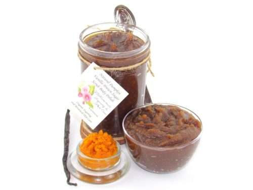 Indulge in the seasonal warmth of an 8 oz jar of pumpkin vanilla brown sugar scrub. The jar is prominently displayed at the center, accompanied by a glass bowl showcasing the scrub's rich texture. To the left, a smaller bowl contains pure pumpkin puree and a whole vanilla bean, highlighting the scrub's natural ingredients.