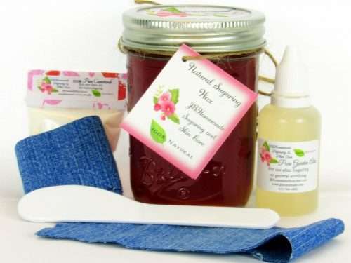 An 8-ounce mason of JBHomemade Sugaring Wax is presented with its included pouch of cornstarch, denim strips, bottle of aloe vera and applicator.