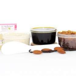 The home sugaring hair removal starter kit comes with a 2 oz tub of firm sugaring paste, a tub of Almond Vanilla Brown Sugar Body Scrub, and a tub of Colloidal Oatmeal Brown Sugar Dry Body Scrub, a small bottle of pure aloe vera, a pouch of cornstarch, an applicator, and the pristine white surface is garnished with almonds and a vanilla bean.