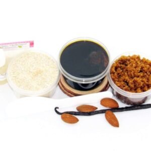 The home sugaring hair removal starter kit comes with a 2 oz tub of firm sugaring paste, a tub of Almond Vanilla Brown Sugar Body Scrub, and a tub of Colloidal Oatmeal Brown Sugar Dry Body Scrub, a small bottle of pure aloe vera, a pouch of cornstarch, an applicator, and the pristine white surface is garnished with almonds and a vanilla bean.