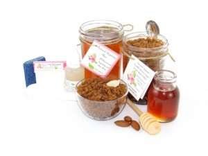 The bundle includes an 8 oz mason jar filled with soft sugaring wax, a jar of Almond Vanilla Brown Sugar Body Scrub, a small bottle of pure aloe vera, a pouch of cornstarch, denim strips, an applicator, and a glass bowl showcasing the sugar scrub, garnished with sprinkled almonds and a small glass jar of raw honey.