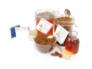 The bundle includes an 8 oz mason jar filled with soft sugaring wax, a jar of Almond Vanilla Brown Sugar Body Scrub, a small bottle of pure aloe vera, a pouch of cornstarch, denim strips, an applicator, and a glass bowl showcasing the sugar scrub, garnished with sprinkled almonds and a small glass jar of raw honey.
