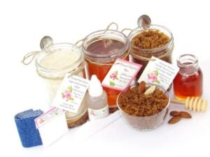 The bundle includes an 8 oz mason jar filled with soft sugaring wax, a jar of Almond Vanilla Brown Sugar Body Scrub, and Colloidal Oatmeal Brown Sugar Dry Body Scrub, a small bottle of pure aloe vera, a pouch of cornstarch, denim strips, an applicator, and a glass bowl showcasing the sugar scrub, garnished with sprinkled almonds and a small glass jar of raw honey.