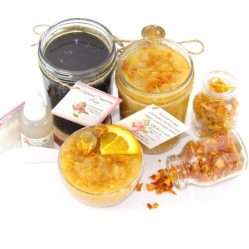 A collection of skincare products including an 8 oz mason jar of sugaring paste and Orange Calendula Herbal Sugar Scrub, accompanied by smaller jars of calendula petals and dried orange zest on a white background.