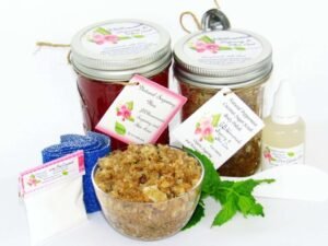 The bundle includes an 8 oz mason jar filled with soft sugaring wax, a jar of Peppermint Coconut Sugar Body Scrub, a small bottle of pure aloe vera, a pouch of cornstarch, denim strips, an applicator, and a glass bowl showcasing the sugar scrub, garnished with coconut shavings and a sprig of fresh mint.