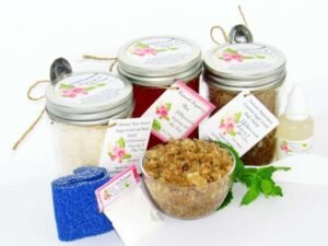 The bundle includes an 8 oz mason jar filled with soft sugaring wax, a jar of Peppermint Coconut Sugar Body Scrub, and Colloidal Oatmeal Brown Sugar Dry Body Scrub, a small bottle of pure aloe vera, a pouch of cornstarch, denim strips, an applicator, and a glass bowl showcasing the sugar scrub, garnished with coconut shavings and a sprig of fresh mint.