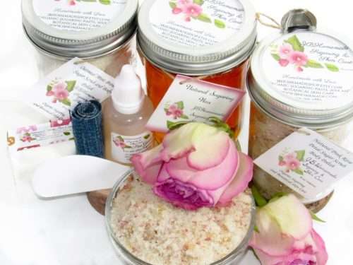 The bundle includes an 8 oz mason jar filled with soft sugaring wax, a jar of Pink Rose Petal Sugar Body Scrub, and Colloidal Oatmeal Brown Sugar Dry Body Scrub, a small bottle of pure aloe vera, a pouch of cornstarch, denim strips, an applicator, and a glass bowl showcasing the sugar scrub, garnished with a pink rose bloom.