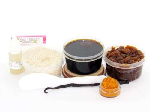 The home sugaring hair removal starter kit comes with a 2 oz tub of firm sugaring paste, a tub of Pumpkin Vanilla Brown Sugar Body Scrub, and a tub of Colloidal Oatmeal Brown Sugar Dry Body Scrub, a small bottle of pure aloe vera, a pouch of cornstarch, an applicator, and the pristine white surface is garnished with a vanilla bean and pumpkin puree.