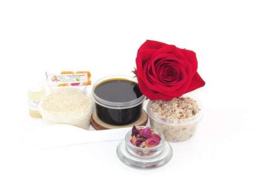 The home sugaring hair removal starter kit comes with a 2 oz tub of firm sugaring paste, a tub of Red Rose Petal Sugar Body Scrub, and a tub of Colloidal Oatmeal Brown Sugar Dry Body Scrub, a small bottle of pure aloe vera, a pouch of cornstarch, an applicator, and a glass bowl garnished with a red rose bloom.