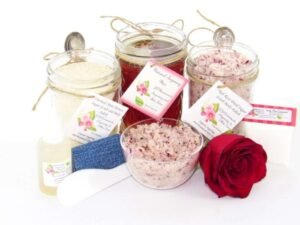 The bundle includes an 8 oz mason jar filled with soft sugaring wax, a jar of Red Rose Petal Sugar Body Scrub, and Colloidal Oatmeal Brown Sugar Dry Body Scrub, a small bottle of pure aloe vera, a pouch of cornstarch, denim strips, an applicator, and a glass bowl showcasing the sugar scrub, garnished with a red rose bloom.