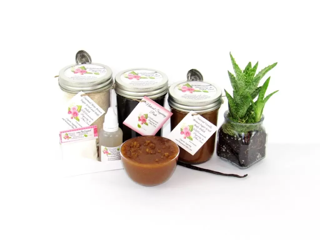The bundle includes an 8 oz mason jar filled with firm sugaring paste, a jar of Vanilla Aloe Brown Sugar Body Scrub, and Colloidal Oatmeal Brown Sugar Dry Body Scrub, a small bottle of pure aloe vera, a pouch of cornstarch, an applicator, and a glass bowl showcasing the sugar scrub, garnished with a vanilla bean and a glass planter with an aloe plant to the right.