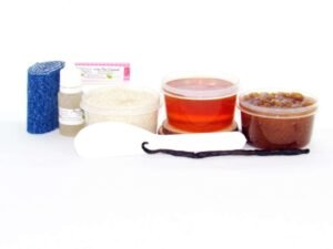 The home sugaring hair removal starter kit comes with a 2 oz tub of soft sugaring wax, a tub of Vanilla Aloe Brown Sugar Body Scrub, a tub of Colloidal Oatmeal Brown Sugar Dry Body Scrub, a small bottle of pure aloe vera, a pouch of cornstarch, denim strips, an applicator, along with a vanilla bean for illustration.