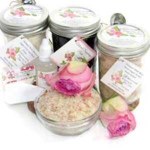 The bundle includes an 8 oz mason jar filled with firm sugaring paste, a jar of Pink Rose Petal Sugar Body Scrub, and Colloidal Oatmeal Brown Sugar Dry Body Scrub, a small bottle of pure aloe vera, a pouch of cornstarch, an applicator, and a glass bowl showcasing the sugar scrub, garnished with a pink rose bloom.