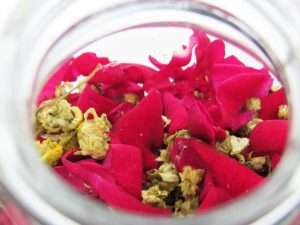 A close-up view of vibrant red rose petals and delicate chamomile flowers ready for infusion.