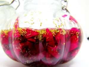Pouring grapeseed oil into the jar, initiating the infusion process with the floral blend.