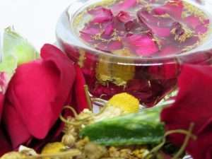 The final image showing infused oil in a glass container amidst scattered slices of fresh aloe vera, roses, and chamomile.