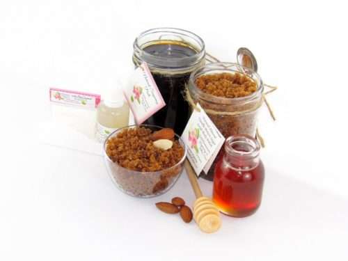 The bundle includes an 8 oz mason jar filled with firm sugaring paste, a jar of Almond Vanilla Brown Sugar Body Scrub, a small bottle of pure aloe vera, a pouch of cornstarch, an applicator, and a glass bowl showcasing the sugar scrub, garnished with sprinkled almonds and a small glass jar of raw honey.