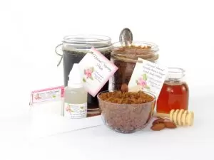 The bundle includes an 8 oz mason jar filled with firm sugaring paste, a jar of Almond Vanilla Brown Sugar Body Scrub, a small bottle of pure aloe vera, a pouch of cornstarch, an applicator, and a glass bowl showcasing the sugar scrub, garnished with sprinkled almonds and a small glass jar of raw honey.