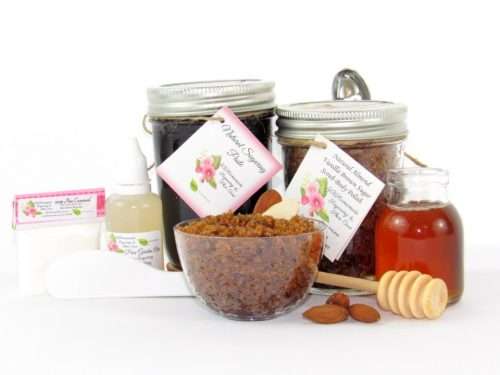The bundle includes an 8 oz mason jar filled with firm sugaring paste, a jar of Almond Vanilla Brown Sugar Body Scrub, a small bottle of pure aloe vera, a pouch of cornstarch, an applicator, and a glass bowl showcasing the sugar scrub, garnished with sprinkled almonds and a small glass jar of raw honey.
