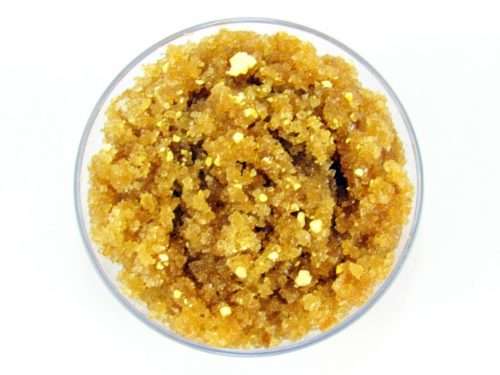 A glass bowl of JBHomemade Sugaring and Skin Care's Natural Lemon Zest Citrus Sugar Body Scrub adorned with sprinkles of dried lemon zest.