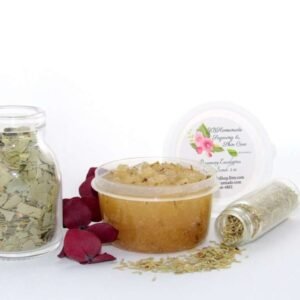 A 2 oz tub of refreshing herbal cane sugar scrub is infused with rosemary and eucalyptus, perfect for rejuvenating weary skin. The accompanying image shows the scrub tub centrally placed, flanked by two smaller glass jars—one filled with dried rosemary, the other with dried eucalyptus—both tipped over, their contents scattered on a pristine white surface. Beside the jar lies a sprig of dried eucalyptus.