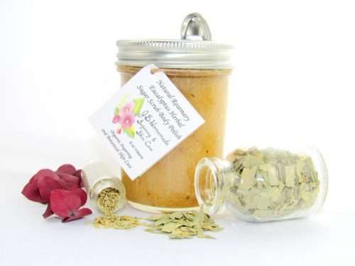 An 8 oz jar of refreshing herbal cane sugar scrub is infused with rosemary and eucalyptus, perfect for rejuvenating weary skin. The accompanying image shows the scrub jar centrally placed, flanked by two smaller glass jars—one filled with dried rosemary, the other with dried eucalyptus—both tipped over, their contents scattered on a pristine white surface. Beside the jar lies a sprig of dried eucalyptus.