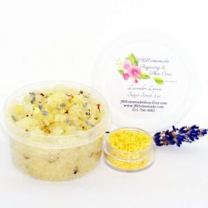 Discover a 2 oz tub of calming cane sugar scrub, a blend of relaxing lavender and invigorating lemon, ideal for a soothing experience. The sugar scrub tub is placed centrally, adorned with dried lemon zest and a lemon slice on top. Flanking the scrub tub is one smaller jar, brimming with dried lemon zest, and a delicate lavender sprig resting in front.