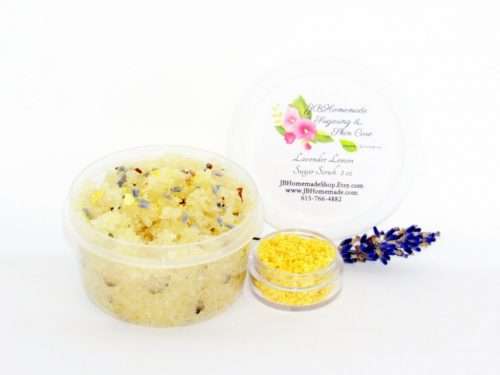 Discover a 2 oz tub of calming cane sugar scrub, a blend of relaxing lavender and invigorating lemon, ideal for a soothing experience. The sugar scrub tub is placed centrally, adorned with dried lemon zest and a lemon slice on top. Flanking the scrub tub is one smaller jar, brimming with dried lemon zest, and a delicate lavender sprig resting in front.