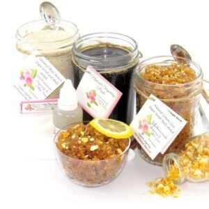 A bundle featuring an 8 oz mason jar of firm consistency sugaring paste, flanked by jars of Lemon Zest Cane Sugar Body Scrub and Colloidal Oatmeal Brown Sugar Dry Body Scrub, with a spilled jar of dried lemon zest and a bowl of the body scrub adorned with a lemon slice.