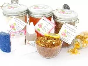 A bundle featuring an 8 oz mason jar of softer consistency sugaring wax, flanked by jars of Lemon Zest Cane Sugar Body Scrub and Colloidal Oatmeal Brown Sugar Dry Body Scrub, a small bottle of pure aloe vera, a pouch of cornstarch, denim strips, an applicator, with a spilled jar of dried lemon zest and a bowl of the body scrub adorned with a lemon slice.