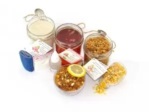 Natural Lemon Zest Sugar Scrub Complete Sugaring Wax & Scrub Bundle – thinner hair A bundle featuring an 8 oz mason jar of softer consistency sugaring wax, flanked by jars of Lemon Zest Cane Sugar Body Scrub and Colloidal Oatmeal Brown Sugar Dry Body Scrub, a small bottle of pure aloe vera, a pouch of cornstarch, denim strips, an applicator, with a spilled jar of dried lemon zest and a bowl of the body scrub adorned with a lemon slice.