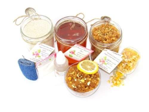 A bundle featuring an 8 oz mason jar of softer consistency sugaring wax, flanked by jars of Lemon Zest Cane Sugar Body Scrub and Colloidal Oatmeal Brown Sugar Dry Body Scrub, a small bottle of pure aloe vera, a pouch of cornstarch, denim strips, an applicator, with a spilled jar of dried lemon zest and a bowl of the body scrub adorned with a lemon slice.
