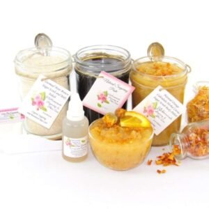 A collection of skincare products including an 8 oz mason jar of sugaring paste, Orange Calendula Herbal Sugar Scrub, and Colloidal Oatmeal Brown Sugar Dry Body Scrub, accompanied by smaller jars of calendula petals and dried orange zest on a white background.