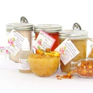 A collection of skincare products including an 8 oz mason jar of sugaring wax, Orange Calendula Herbal Sugar Scrub, and Colloidal Oatmeal Brown Sugar Dry Body Scrub, a small bottle of pure aloe vera, a pouch of cornstarch, denim strips, an applicator, accompanied by smaller jars of calendula petals and dried orange zest on a white background.