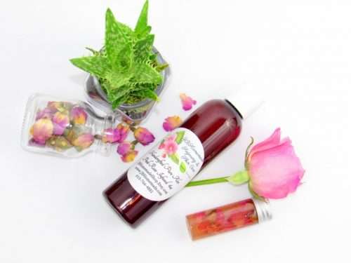 An overhead perspective of a 4 oz bottle of handcrafted Radiant Rose Glow: Pure Aloe Vera Infused with Pink Rose Petals with natural ingredients of pink rose petals and an aloe vera plant visible.