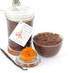 Indulge in the seasonal warmth of an 8 oz jar of pumpkin vanilla brown sugar scrub. The jar is prominently displayed at the center, accompanied by a glass bowl showcasing the scrub's rich texture. To the left, a smaller bowl contains pure pumpkin puree and a whole vanilla bean, highlighting the scrub's natural ingredients.
