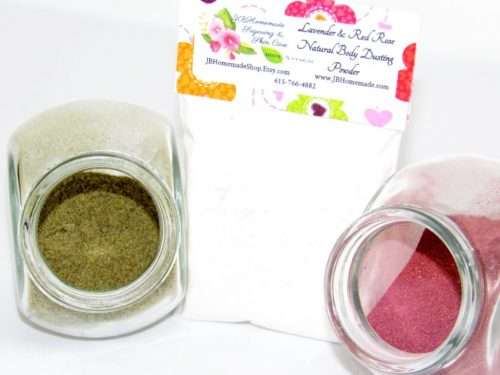 A close-up view of the all-natural ingredients including lavender and red rose for the Naturally Serene body dusting powder, displayed in a tilted glass bowl.