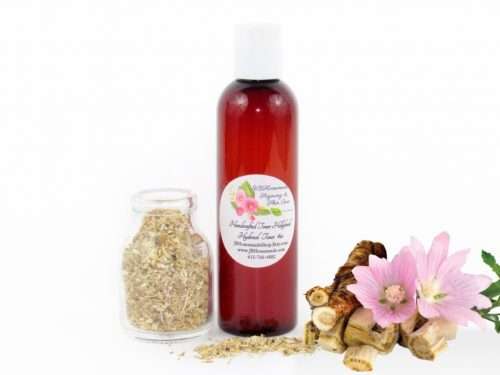 A bottle of JBHomemade’s handcrafted hollyhock water toner, made with organic marshmallow root and fresh hollyhock blooms, accompanied by dried marshmallow root and a vibrant hollyhock flower.