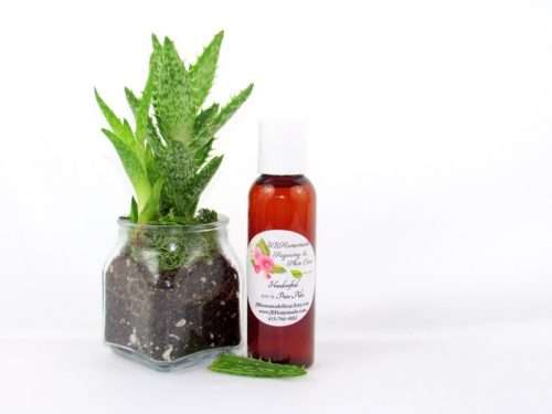 A 2 oz amber bottle of Pure Aloe Vera product, enriched and authentic, surrounded by fresh aloe vera leaf pieces, showcasing the natural ingredients and the premium quality of the product.