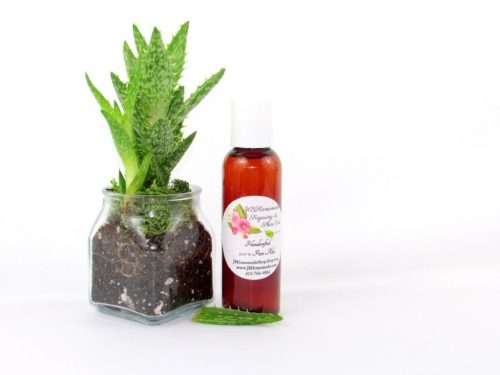A 2 oz amber bottle of Pure Aloe Vera product, enriched and authentic, surrounded by fresh aloe vera leaf pieces, showcasing the natural ingredients and the premium quality of the product.