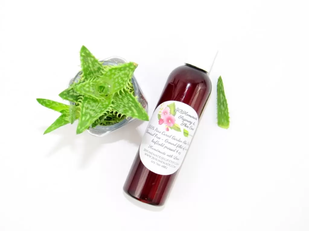 A 4 oz amber bottle of Pure Aloe Vera product, enriched and authentic, surrounded by fresh aloe vera leaf pieces, showcasing the natural ingredients and the premium quality of the product.