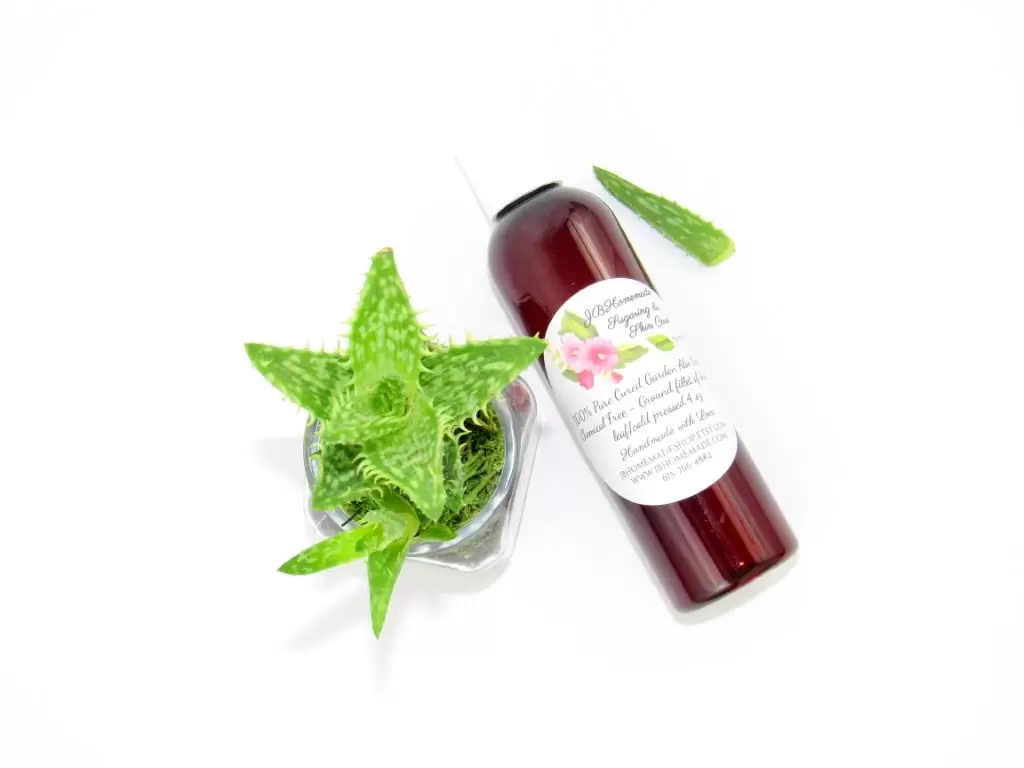 A 4 oz amber bottle of Pure Aloe Vera product, enriched and authentic, surrounded by fresh aloe vera leaf pieces, showcasing the natural ingredients and the premium quality of the product.