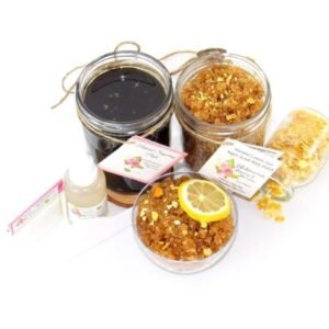 A bundle featuring an 8 oz mason jar of firm consistency sugaring paste, paired with a jar of Lemon Zest Cane Sugar Body Scrub. and Colloidal Oatmeal Brown Sugar Dry Body Scrub, with a spilled jar of dried lemon zest and a bowl of the body scrub adorned with a lemon slice.