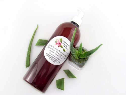 A 32 oz amber pump bottle of Pure Aloe Vera product, enriched and authentic, surrounded by fresh aloe vera leaf pieces, showcasing the natural ingredients and the premium quality of the product.