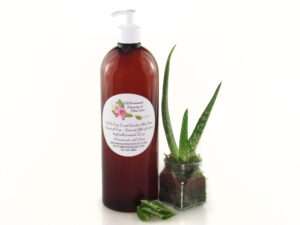 A 32 oz amber pump bottle of Pure Aloe Vera product, enriched and authentic, surrounded by fresh aloe vera leaf pieces, showcasing the natural ingredients and the premium quality of the product.